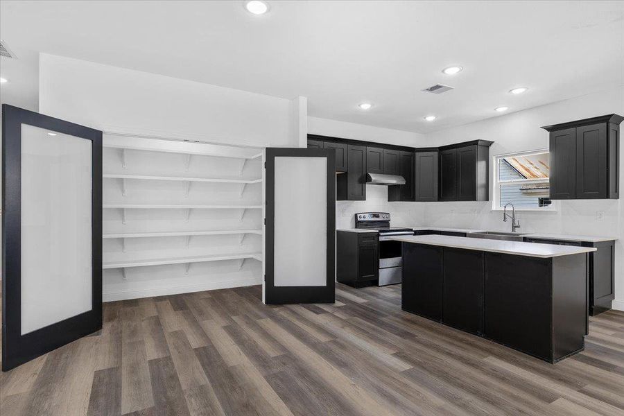 Crisp white walls contrast with dark cabinetry and rich wood-plank flooring in this open layout. Crisp white walls contrast with dark cabinetry and rich wood-plank flooring in this open layout.