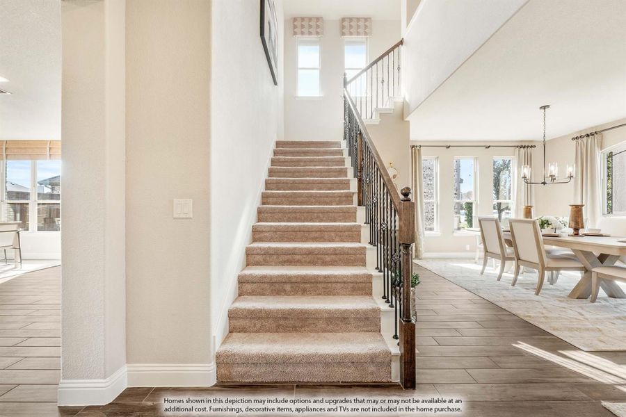 Carpeted staircase with wrought iron railing leading to second floor, open dining room visible to the right Carpeted staircase with wrought iron railing leading to second floor, open dining room visible to the right