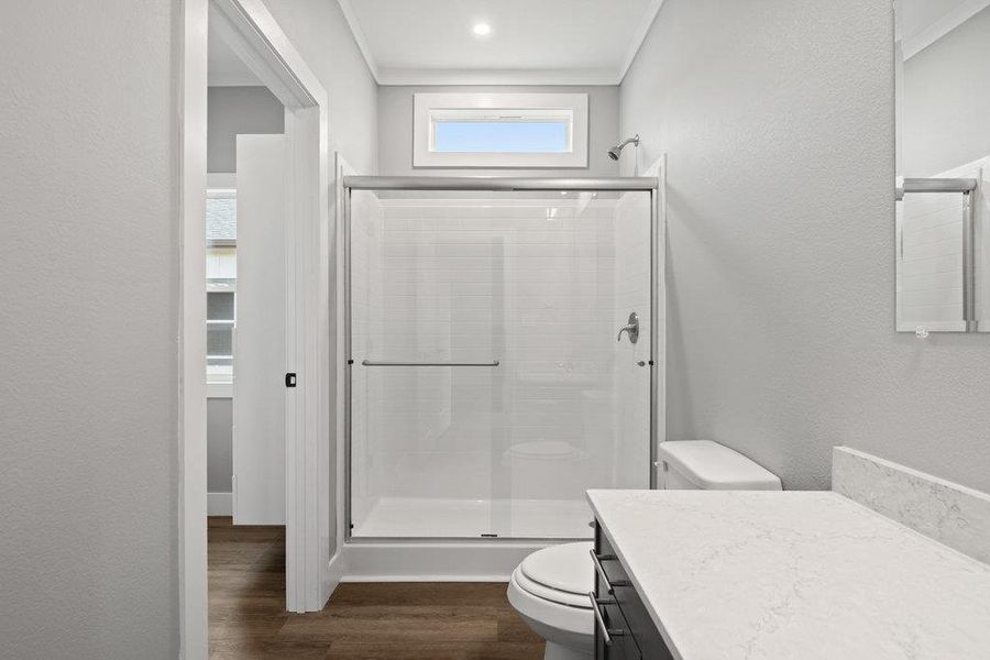 Full bathroom featuring vanity, a stall shower, dark wood finished floors, and a textured wall