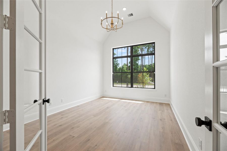 Versatile home office features soaring ceilings and elegant French doors - complete with a closet, making it ideal for a private study or guest room