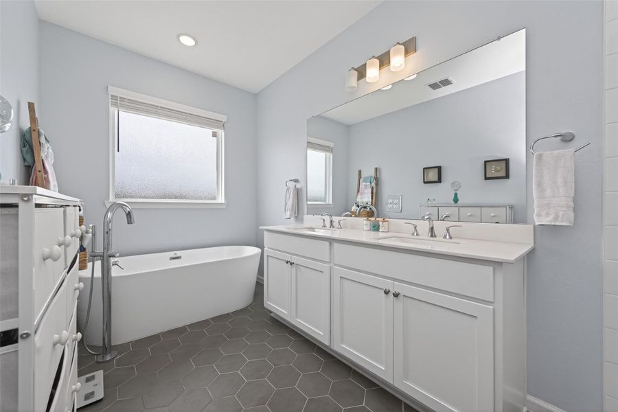 Well-designed primary bathroom with double vanity and soaking tub