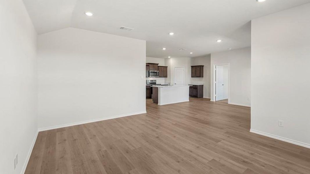 Spacious living area featuring wood-finish flooring, recessed lighting, and a neutral color palette