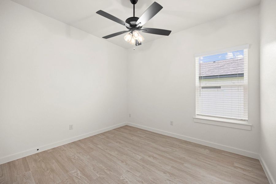 Wood flooring and a ceiling fan create a comfortable, versatile bedroom.