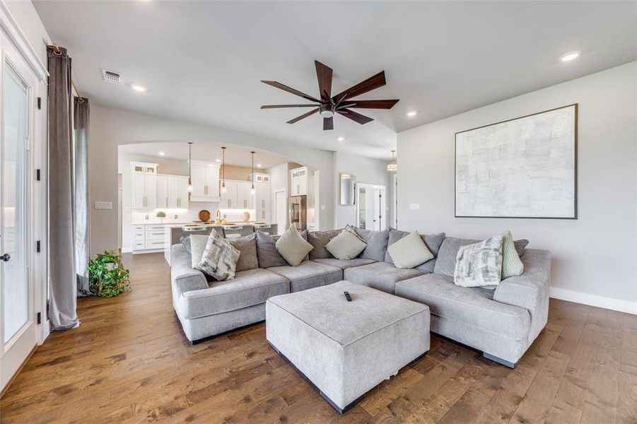 Living room with arched walkways, a ceiling fan, dark wood-type flooring, and recessed lighting