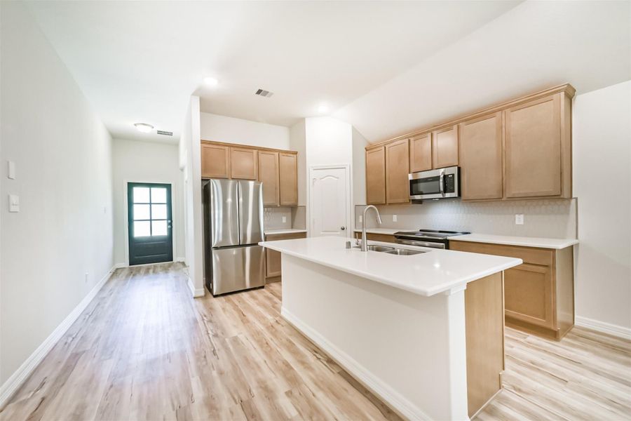 An alternate view of the kitchen showcases the sleek quartz countertops and large island with a breakfast bar, offering plenty of room for stool seating and a quick, casual dining option. An alternate view of the kitchen showcases the sleek quartz countertops and large island with a breakfast bar, offering plenty of room for stool seating and a quick, casual dining option.