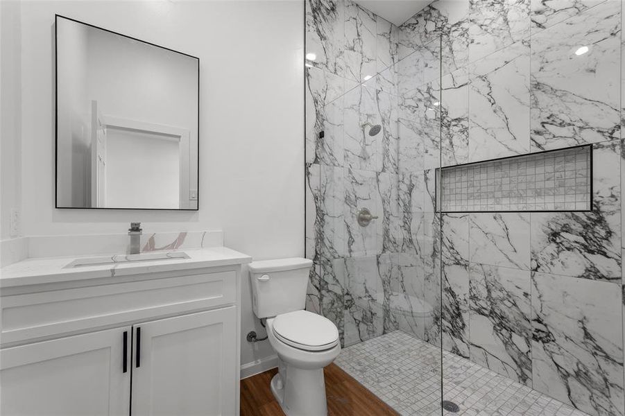 Bathroom with a marble finish shower, vanity, and dark wood-style floors