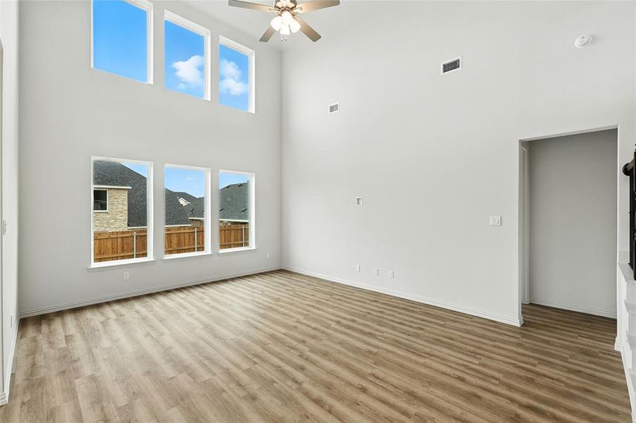 Empty room featuring a high ceiling, light wood-style flooring, and ceiling fan Empty room featuring a high ceiling, light wood-style flooring, and ceiling fan
