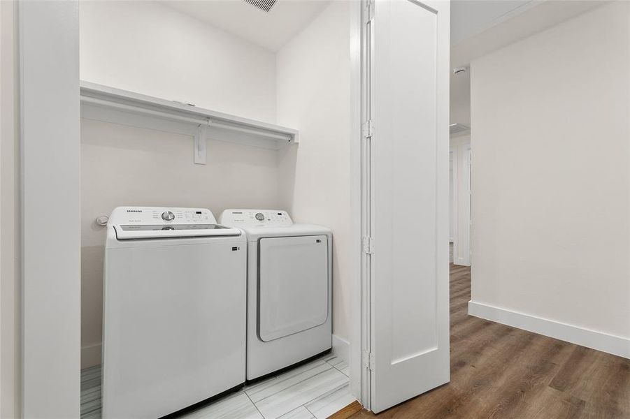 Washroom with washing machine and dryer and wood finished floors Washroom with washing machine and dryer and wood finished floors