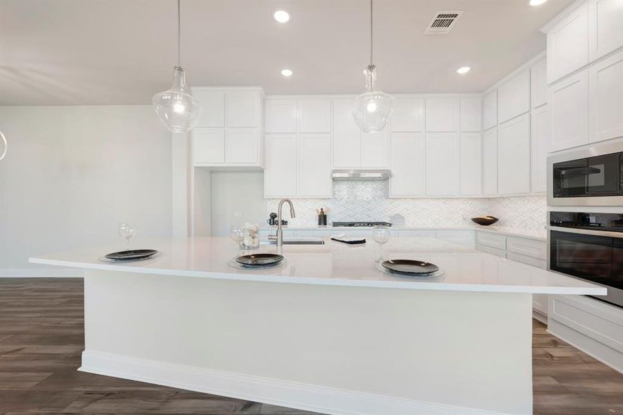 Kitchen featuring dark wood-style flooring, white cabinets, hanging light fixtures, and stainless steel appliances
