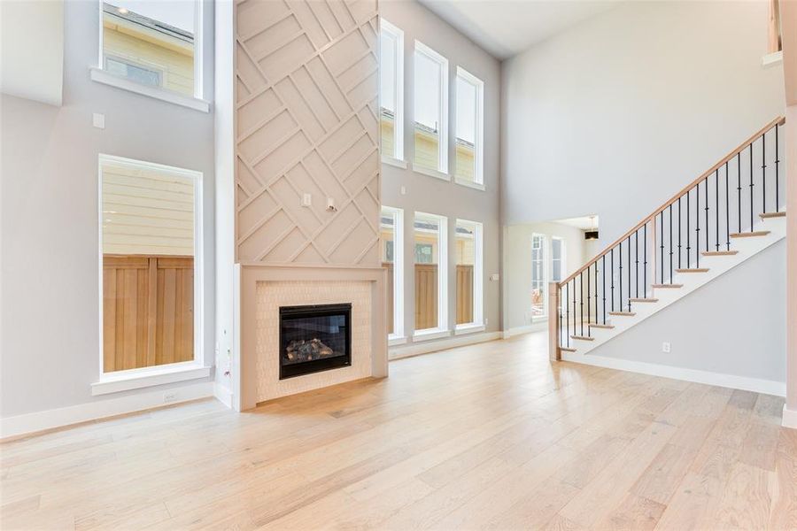 Unfurnished living room featuring a tiled fireplace, light wood-type flooring, and a healthy amount of sunlight