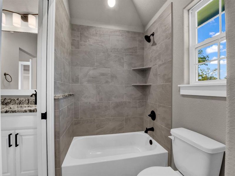 Bathroom featuring  shower combination, vanity, a textured wall, and lofted ceiling