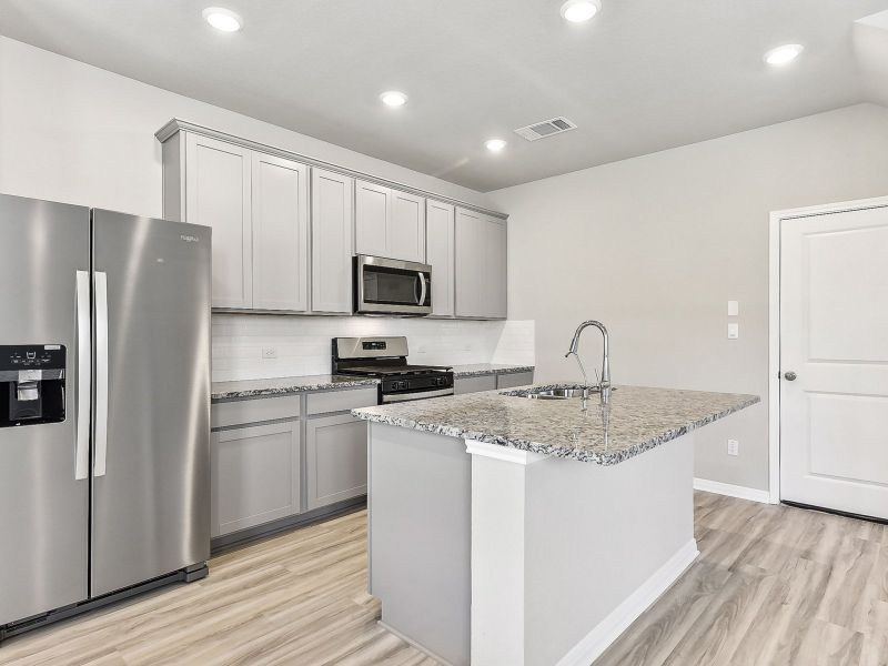 This kitchen features grey stone-colored cabinets and granite countertops.