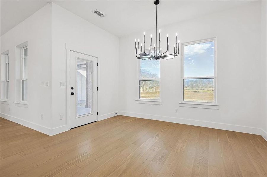 Unfurnished dining area featuring a chandelier and light wood-type flooring