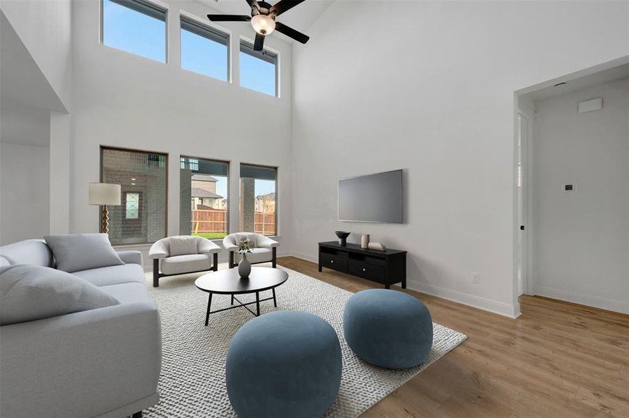 Living area with light wood-style floors, a ceiling fan, and a high ceiling