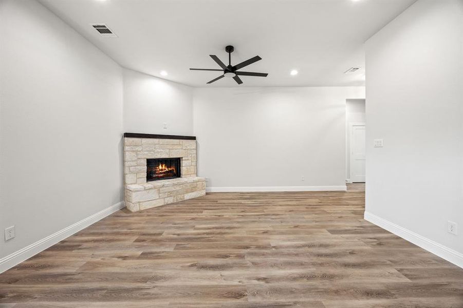 Unfurnished living room featuring a stone fireplace, light wood-style flooring, recessed lighting, and ceiling fan