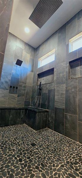 Bathroom featuring stone,
3 shower heads and tiled shower Bathroom featuring stone,
3 shower heads and tiled shower