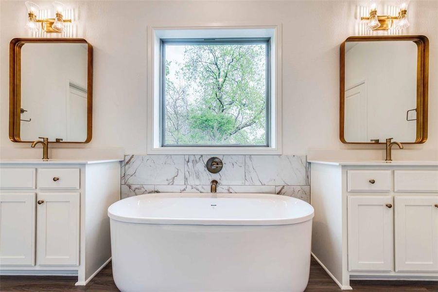 Bathroom featuring a healthy amount of sunlight, dual bowl vanity, and hardwood / wood-style floors