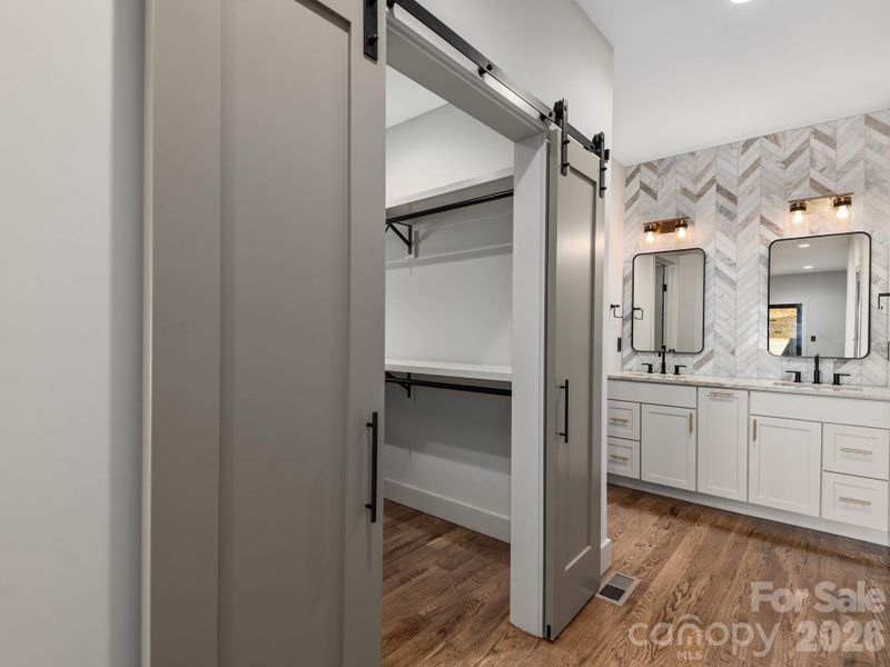 Representative photo from 50 Verde Drive showing the builder’s quality of construction and finish level, including a primary ensuite with spacious walk-in closet, wood shelving, sliding barn doors, Wolf cabinetry, granite countertops, and a designer tiled accent wall.