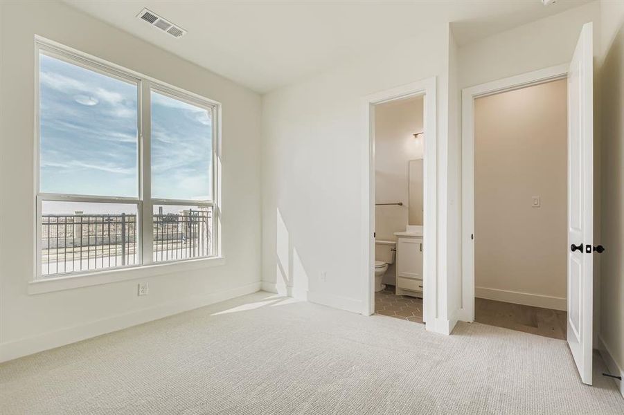 Unfurnished bedroom featuring light carpet and connected bathroom
