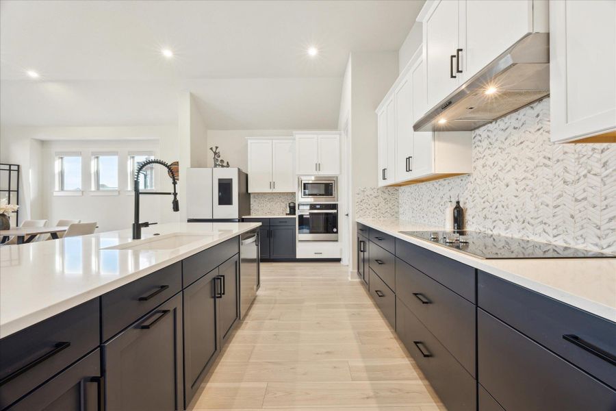 Kitchen featuring quartz countertops, decorative backsplash, and plenty of cabinets for storage.