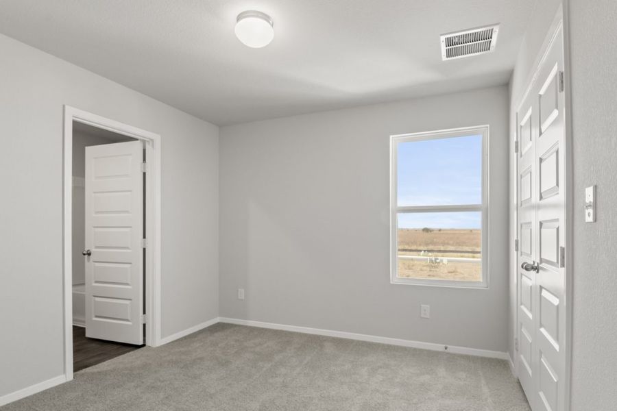 Image of a bedroom with light grey walls, tan carpeting, and a window Image of a bedroom with light grey walls, tan carpeting, and a window