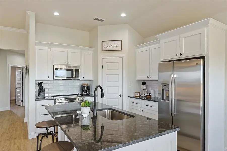Kitchen featuring a central island with an undermount sink, granite countertop, and black faucet Kitchen featuring a central island with an undermount sink, granite countertop, and black faucet