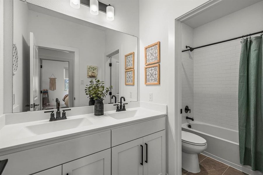 Full bathroom ( secondary) featuring shower / tub combo, double vanity, and dark tile patterned flooring