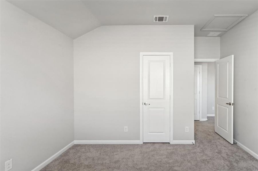 Unfurnished bedroom featuring light colored carpet and vaulted ceiling