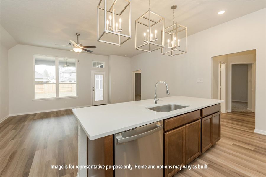 Kitchen with stainless steel dishwasher, hanging light fixtures, an island with sink, a chandelier, and light wood-style floors