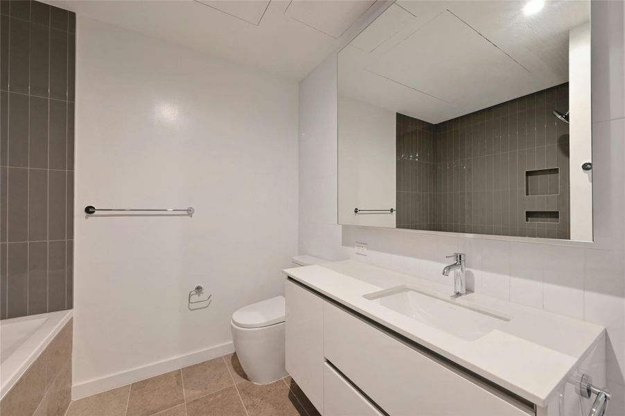 Full secondary bathroom with tile patterned floors, vanity, baseboards, and toilet