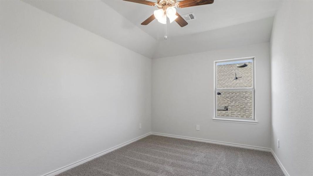 Spare room with carpet flooring, a ceiling fan, and vaulted ceiling