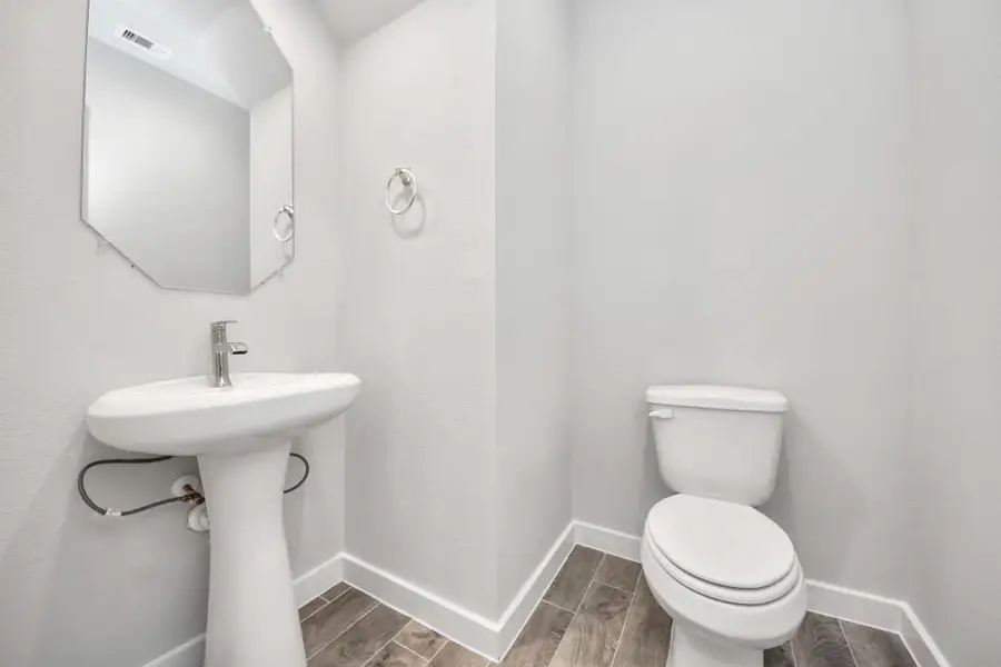 This half bathroom features a stylish pedestal sink, modern hardware, and bright recessed lighting, creating a sleek and inviting space. Sample photo of completed home with similar floor plan. Actual colors and selections may vary. This half bathroom features a stylish pedestal sink, modern hardware, and bright recessed lighting, creating a sleek and inviting space. Sample photo of completed home with similar floor plan. Actual colors and selections may vary.