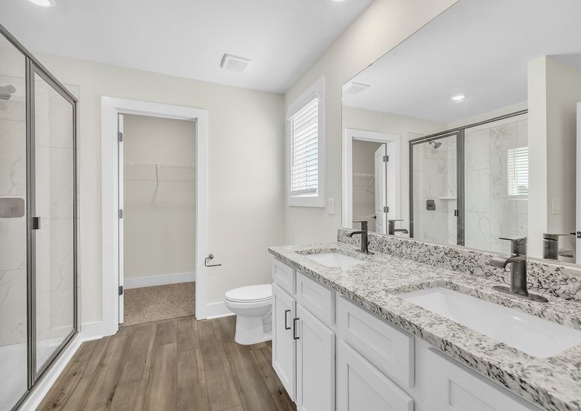 The master bathroom has dual sinks and a glass-enclosed shower.