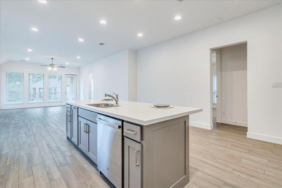 The kitchen features a center island with a sink, a dishwasher, and ample cabinet space, complemented by light-toned flooring