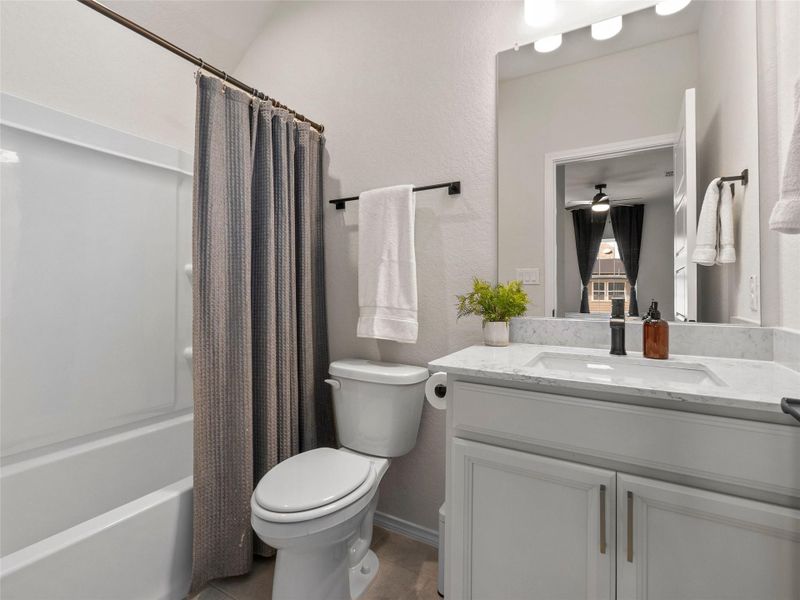 Bathroom with a textured wall, vanity, and shower / bath combo