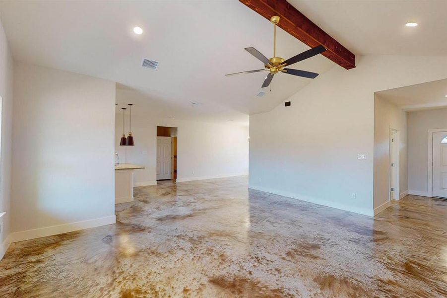 Empty room with ceiling fan, lofted ceiling with beams, and concrete floors