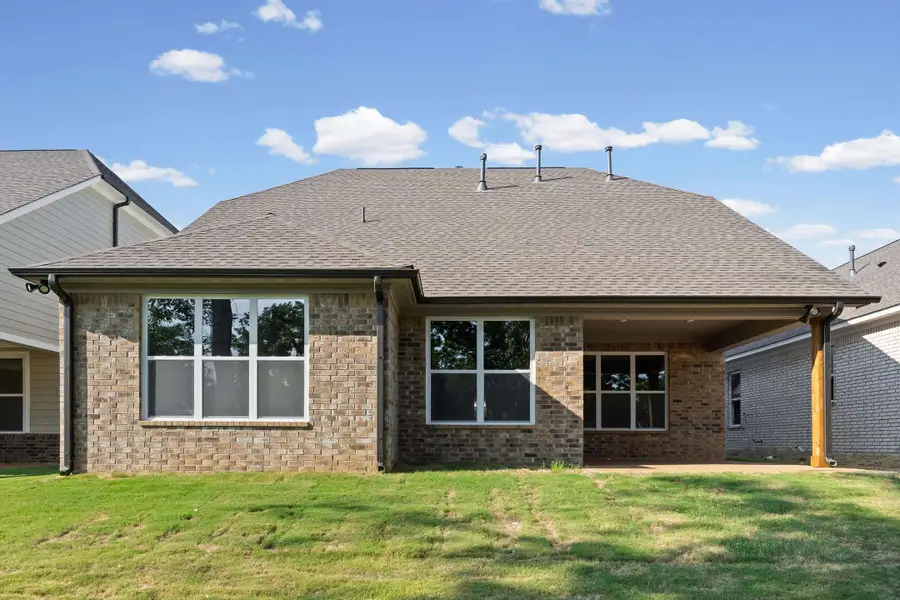 Brick exterior with a covered patio, a shingle roof, and multiple large windows Brick exterior with a covered patio, a shingle roof, and multiple large windows