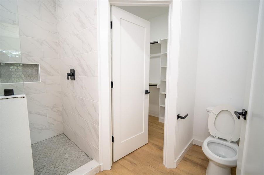 Bathroom featuring tiled shower, toilet, and hardwood / wood-style flooring