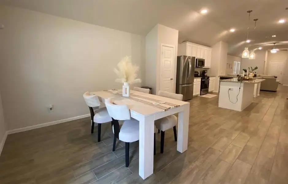 Dining area featuring light wood-style floors, lofted ceiling, and recessed lighting Dining area featuring light wood-style floors, lofted ceiling, and recessed lighting
