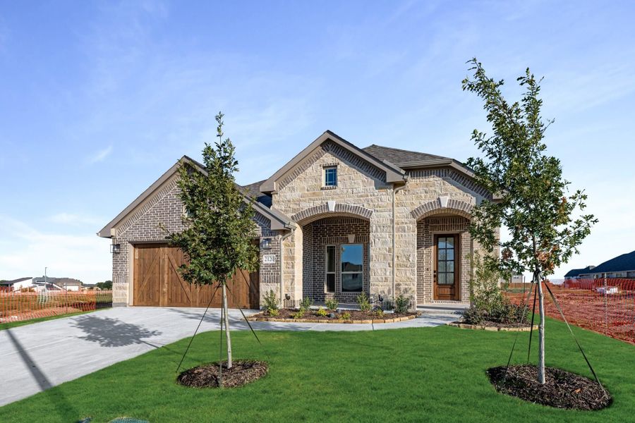 Single-story home with brick and stone exterior, two-car garage, arched entry, and newly landscaped front yard with young trees. Single-story home with brick and stone exterior, two-car garage, arched entry, and newly landscaped front yard with young trees.