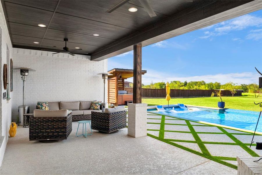 Fenced backyard featuring an outdoor hangout area, ceiling fan, with fireplace