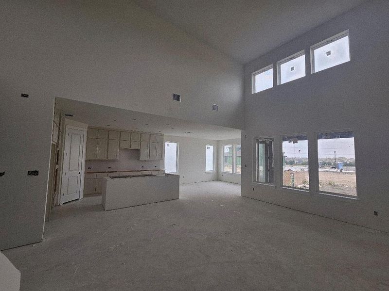 Unfurnished living room featuring plenty of natural light and a towering ceiling Unfurnished living room featuring plenty of natural light and a towering ceiling