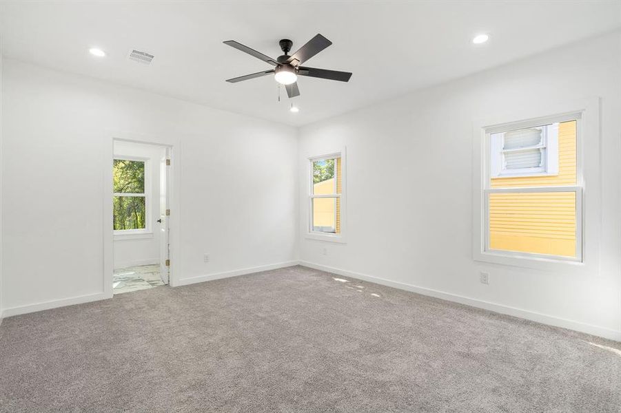 Carpeted spare room with ceiling fan and a healthy amount of sunlight