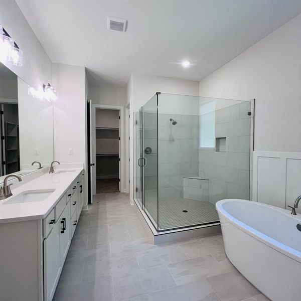 Dual vanity with undermount sinks and brushed nickel fixtures, glass-enclosed shower with tile surround and bench, freestanding bathtub, tile flooring, and recessed lighting Dual vanity with undermount sinks and brushed nickel fixtures, glass-enclosed shower with tile surround and bench, freestanding bathtub, tile flooring, and recessed lighting