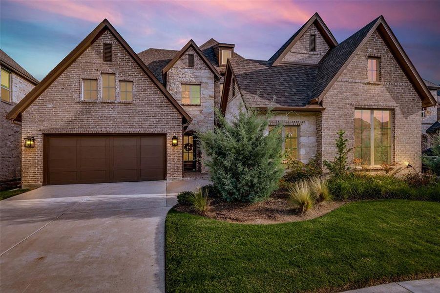 View of front facade with a lawn, brick siding, driveway, and a garage