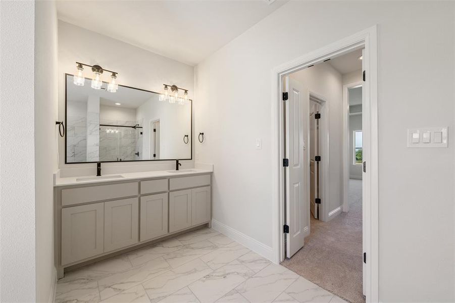 Bathroom featuring marble look tiles, a marble finish shower, and double vanity