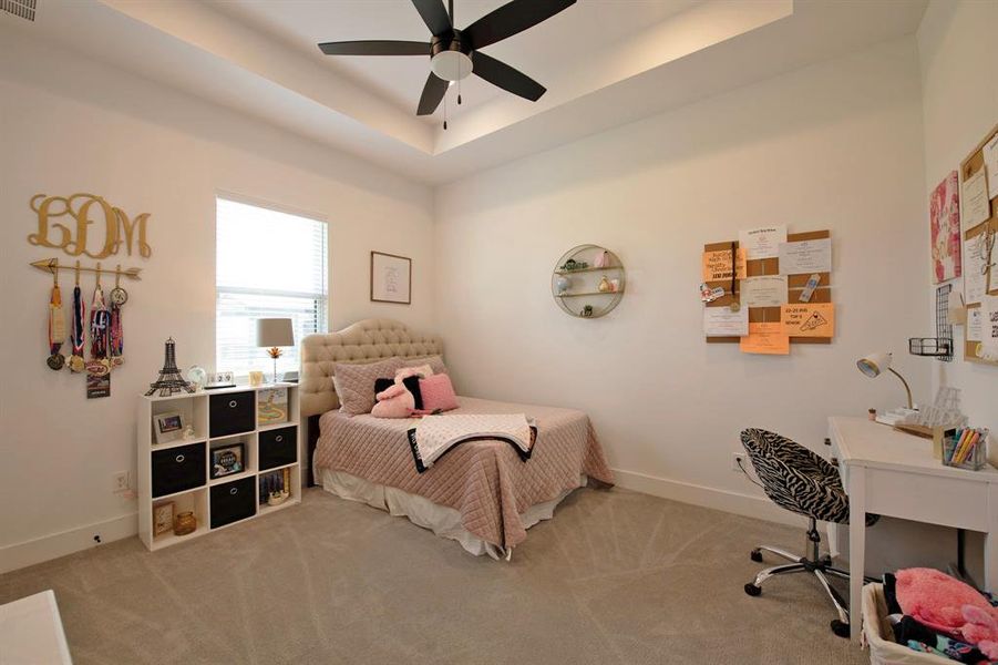Bedroom with a raised ceiling, carpet floors, a ceiling fan, and an office area