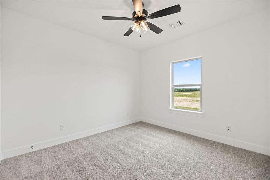 Carpeted spare room featuring baseboards and a ceiling fan Carpeted spare room featuring baseboards and a ceiling fan