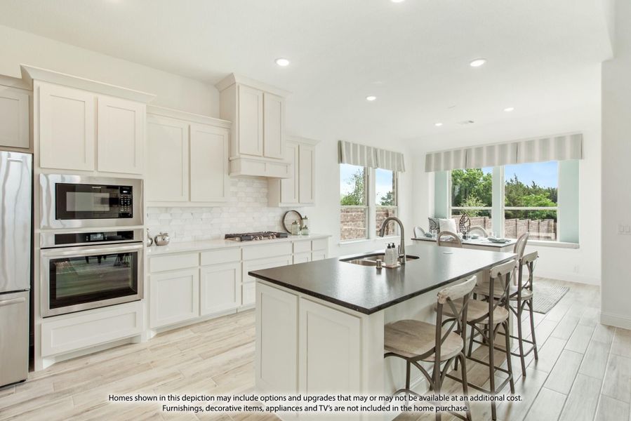 Kitchen with white cabinets, dark island with seating, stainless steel appliances, and tile backsplash