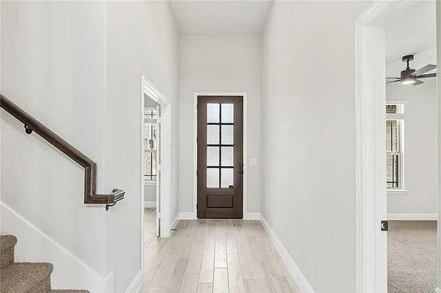 Entrance foyer with baseboards, ceiling fan, stairs, and light wood-style flooring